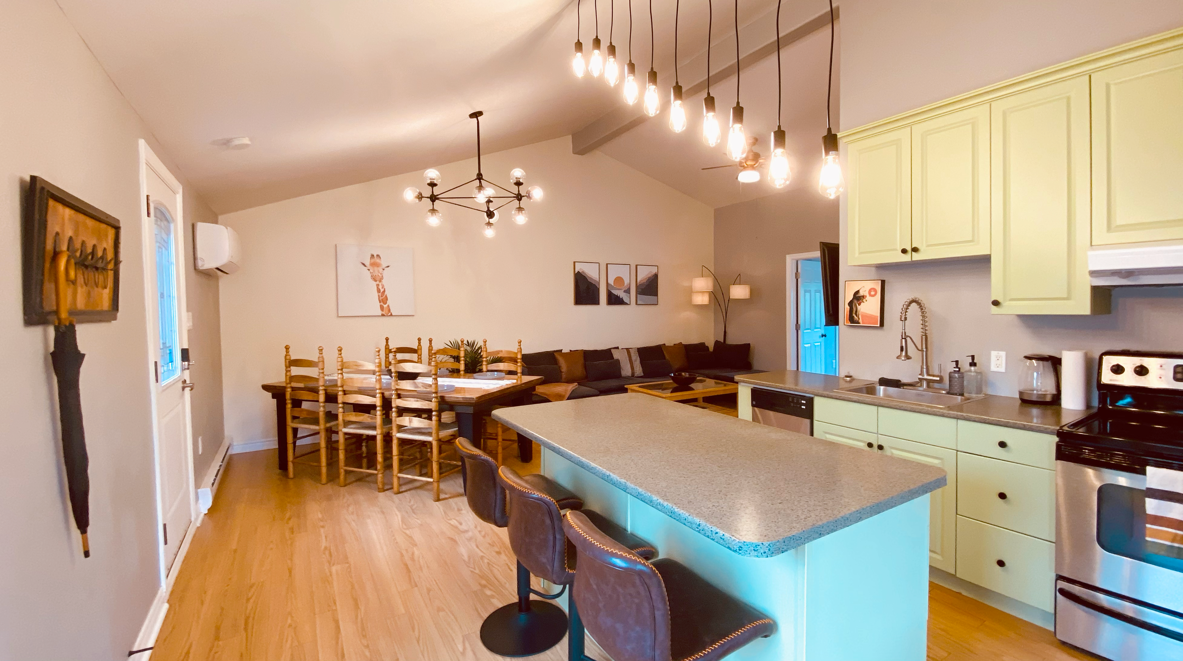 Beautiful open concept kitchen, dining area and livingroom. Kitchen island, large dining table that seats 8, large comfortable mid-centruy-modern sofa, high cathedral ceilings and stylish lighting.